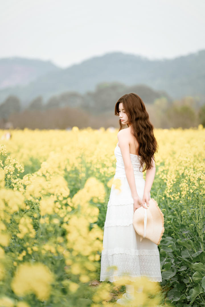 站在油菜花田中的美女大学生个性艺术照